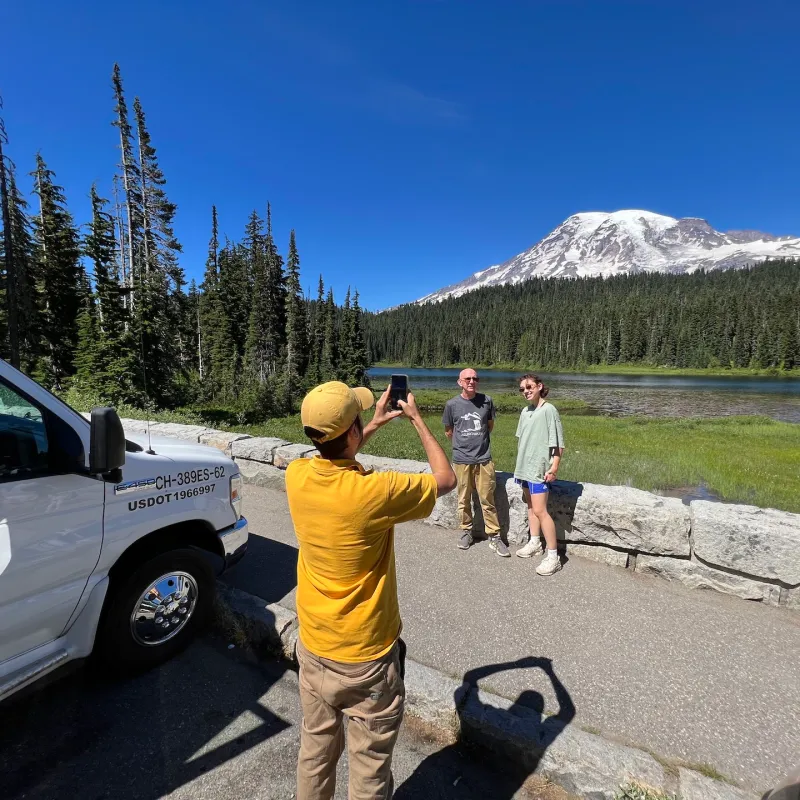 person taking a photo of people in front of trees and Mt. Rainier during a Tours Northwest guided tour