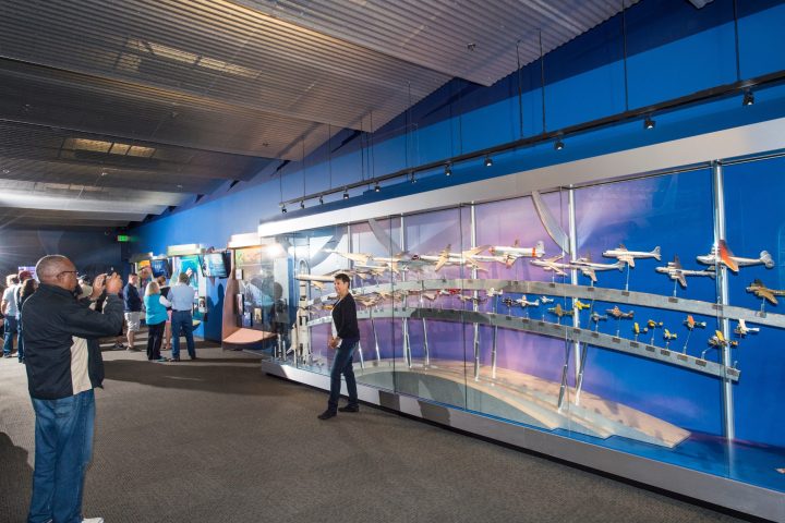 people taking photos of small planes on the wall