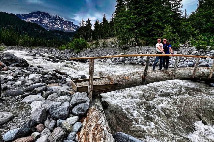 two men posing for phot while crossing Nisqually Bridge with Mt. Rainier in background