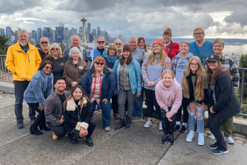 a group of people on a Seattle City Tour posing for a photo with the Seattle skyline in the background
