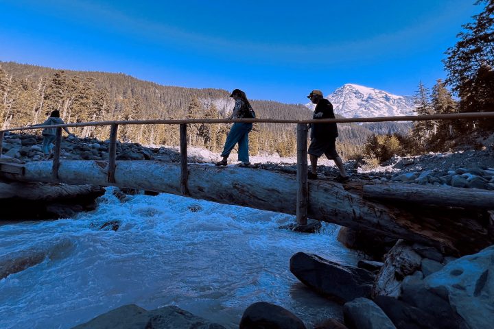 people walking across a wood bridge over a river