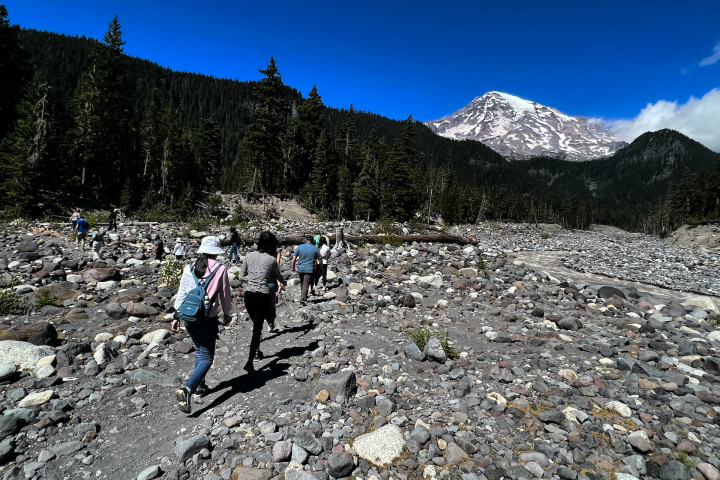 people hiking up a rocky trail towards a mountain