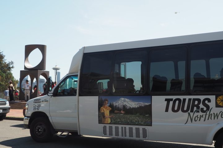 the Seattle tour bus parked on the side of a road with the Space Needle in the background