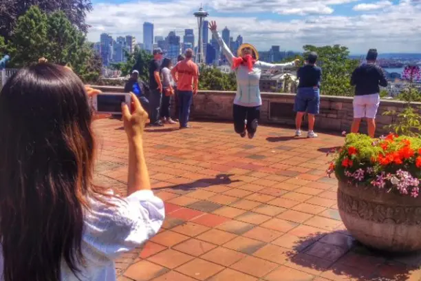 a woman jumping and posing for the camera in front of Seattle skyline