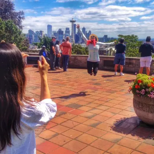 a woman jumping and posing for the camera with city in background during a Seattle Tour