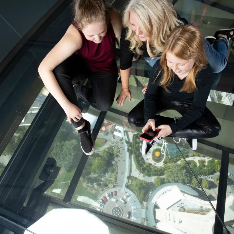 happy people taking a photo through a glass floor at the Seattle Space Needle which is one of the many great Seattle Activities