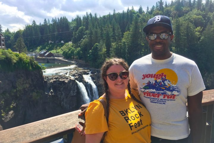 a man and a woman standing in front of a large waterfall