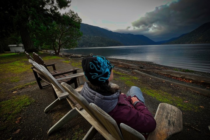 a person sitting on a bench next to a body of water