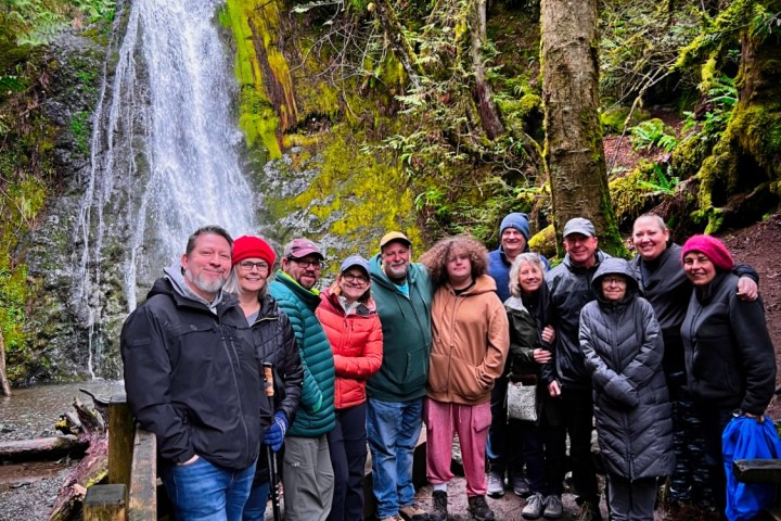 a group of people standing next to a waterfall