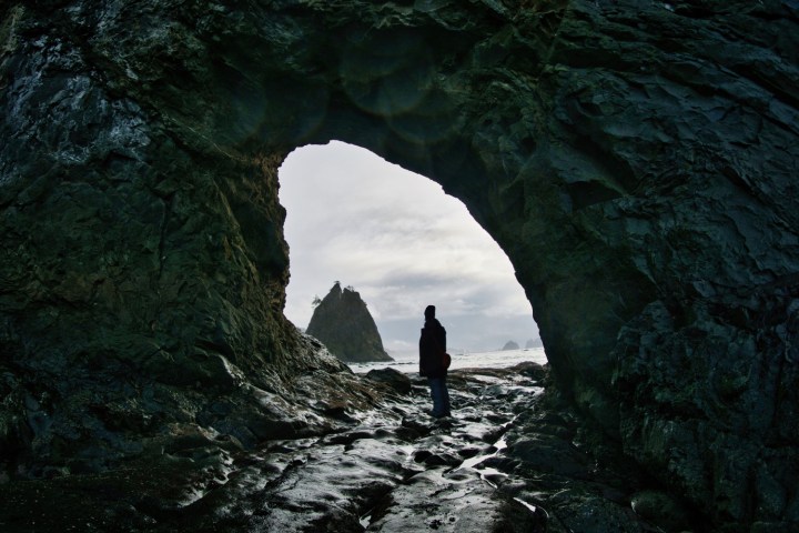 a person standing in front of a large rock
