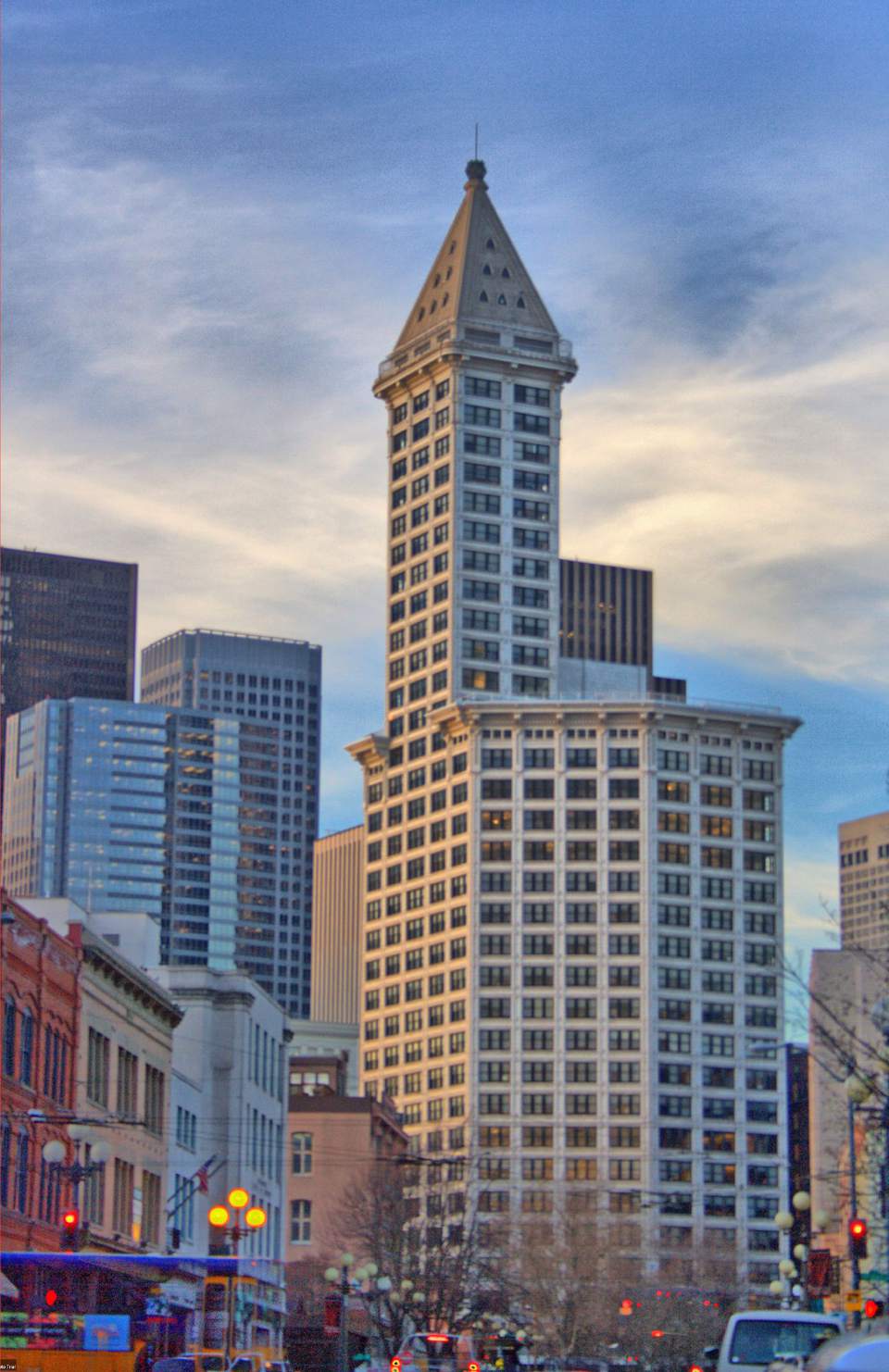 a close up of a busy city street with tall buildings and Smith Tower observatory in the background