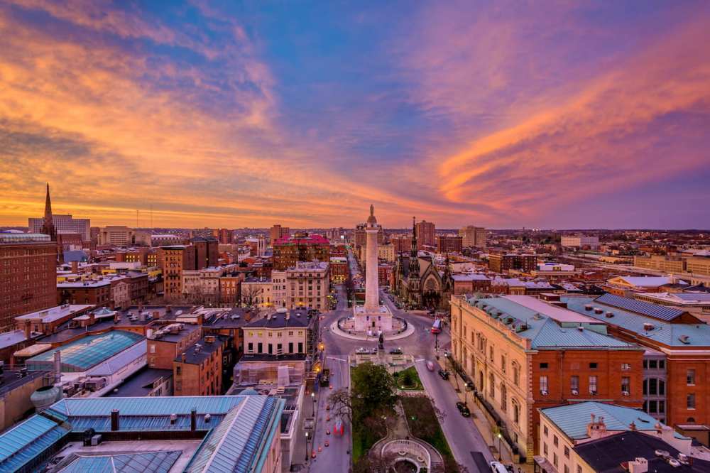 Aerial view of a cityscape with a monument and colorful sunset sky.