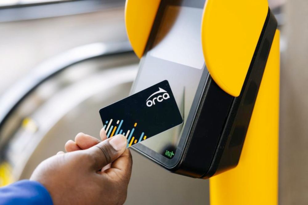 Hand tapping a card on a yellow scanner.